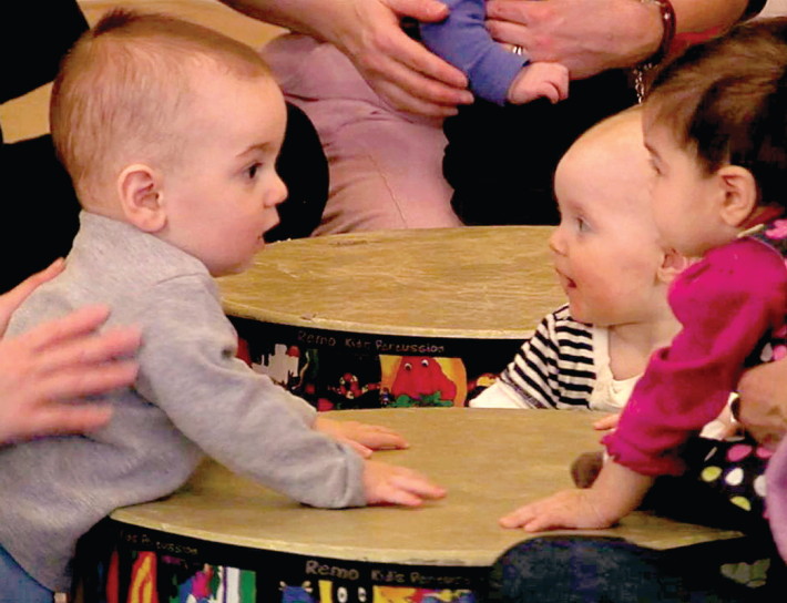 Two babies are playing with a ball on the table.